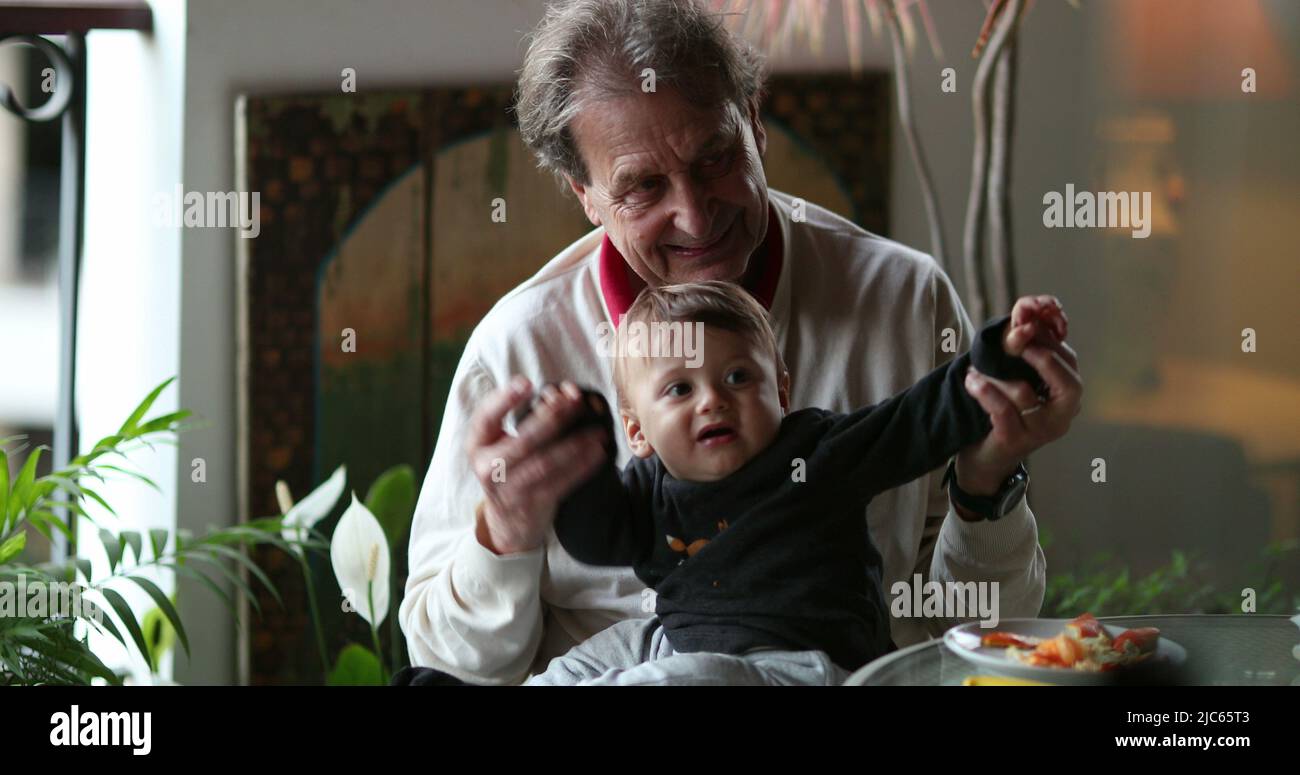 Grand-père décontracté avec bébé petit-fils à la maison balcon, choqué pleurs bébé garçon avec grand-père genoux Banque D'Images