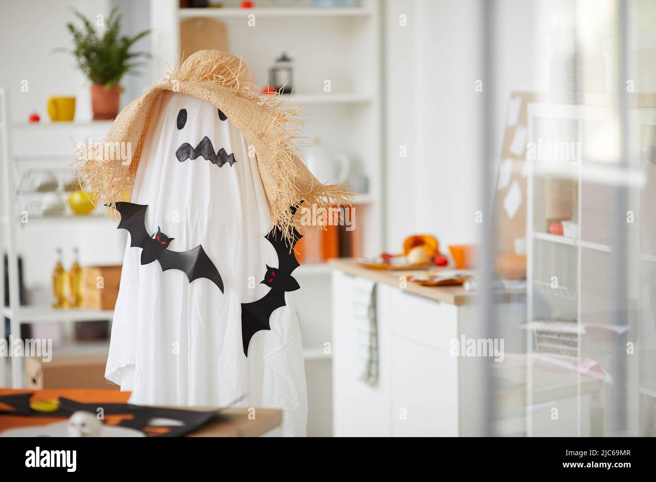 Enfant méconnaissable en costume d'Halloween effrayant de fantôme défait avec des rats noirs en papier debout dans wotkshop Banque D'Images