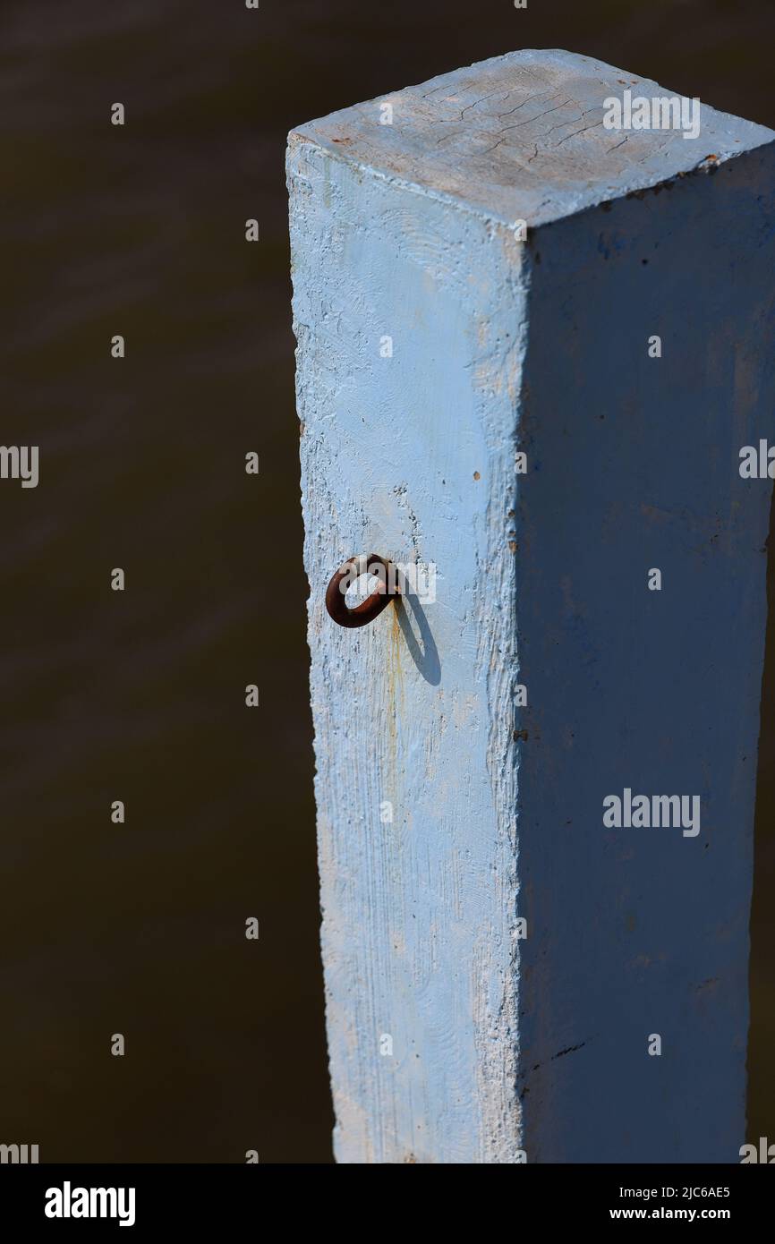 Poteau en béton gros plan avec crochets à chaînes sur la jetée, poteau bleu Jetty, piliers de quai en béton bleu avec lumière du soleil. Banque D'Images