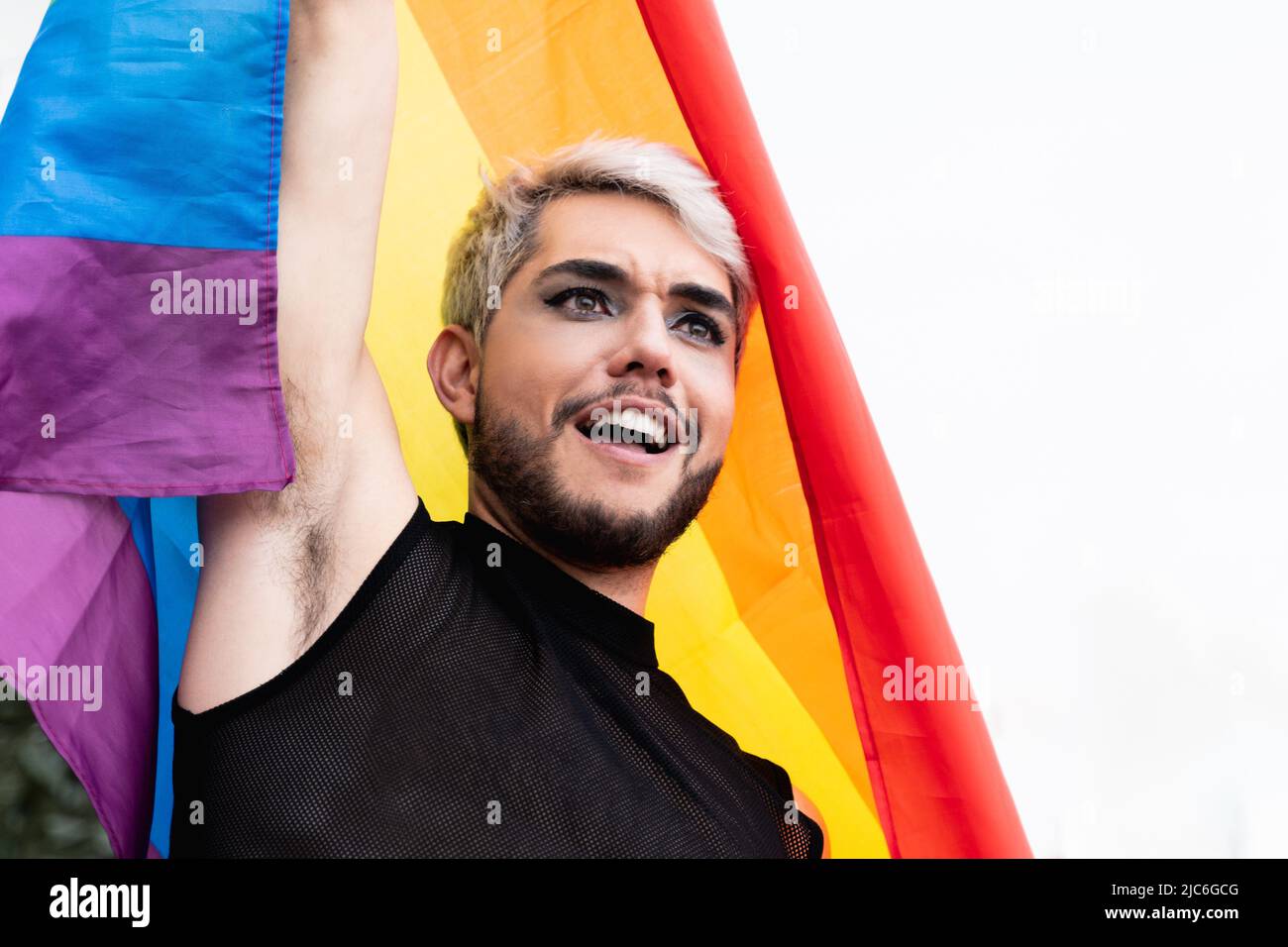 Gay homme transgenre avec maquillage tenant arc-en-ciel drapeau extérieur - LGBTQ Drag queen concept Banque D'Images
