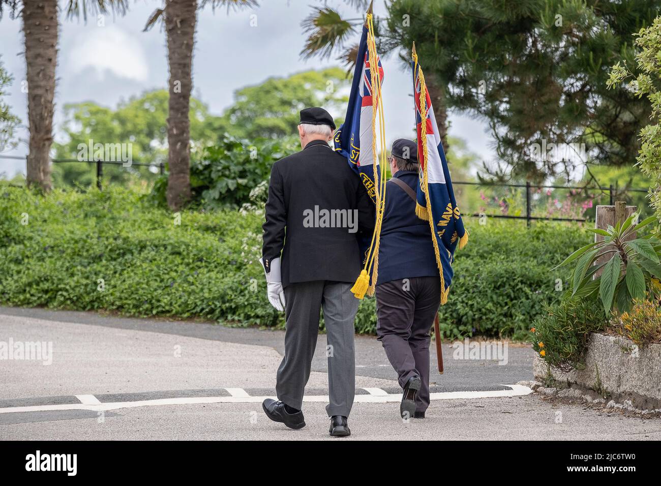 Des porteurs de qualité mûrs portant les drapeaux de leur association militaire marchant jusqu'au début de la parade lors de la Journée militaire au jardin de Trebah, en Cornouailles Banque D'Images