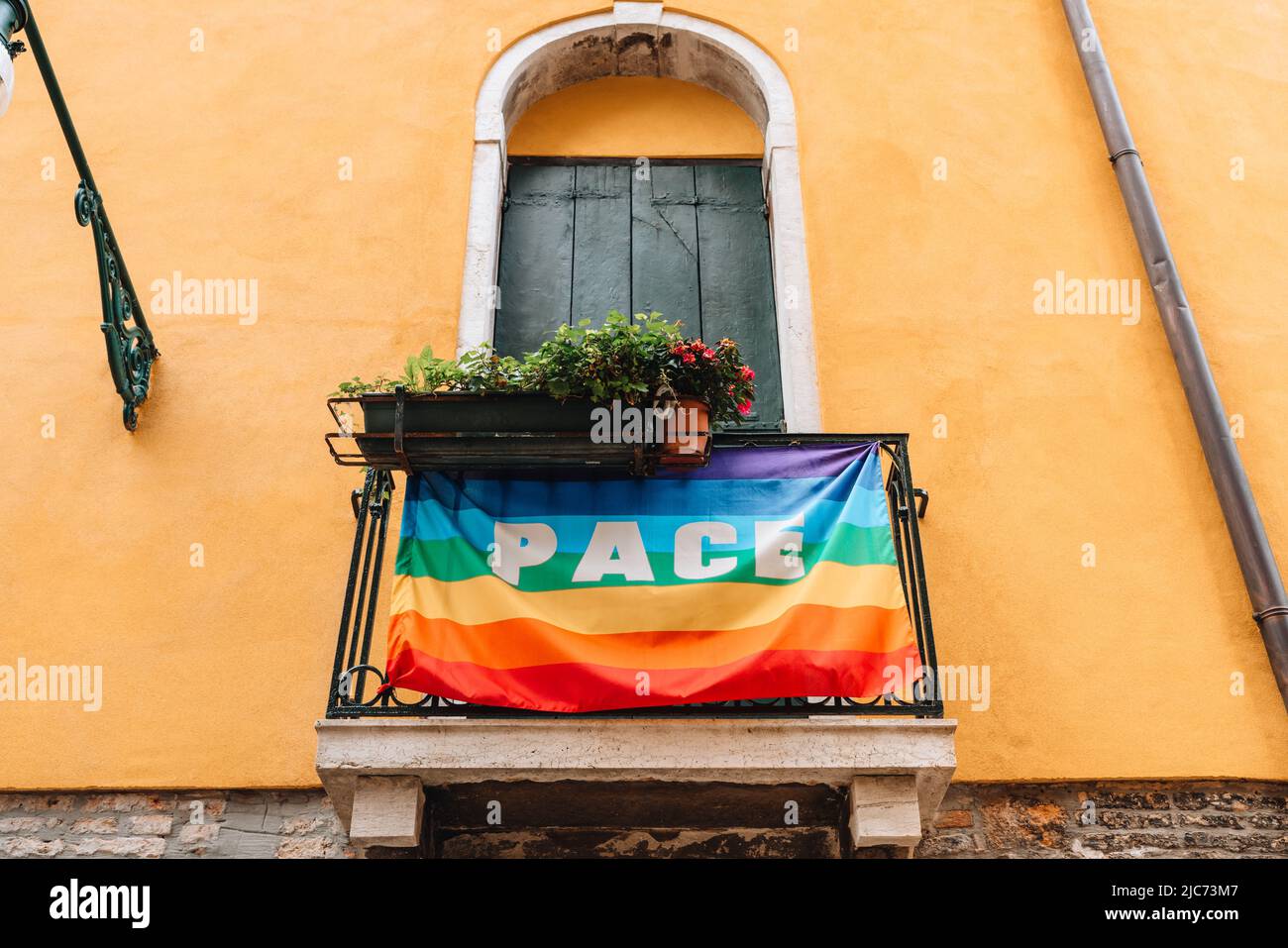 Drapeau arc-en-ciel avec un mot Pace (paix) donnant sur les balustrades d'un bâtiment à Venise, Italie. Banque D'Images