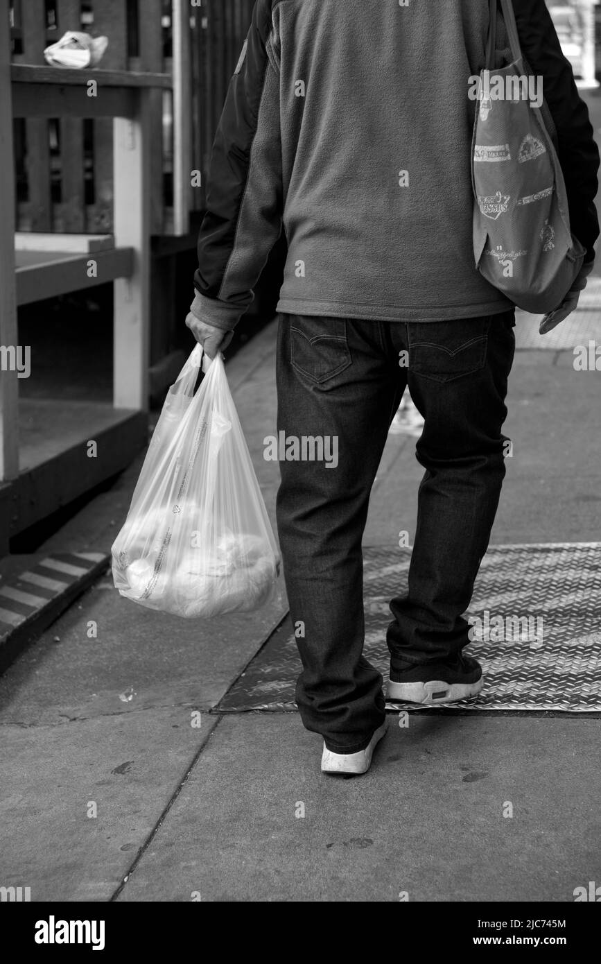 Un homme sino-américain porte un sac d'épicerie le long d'un trottoir dans le quartier chinois de San Francisco, en Californie. Banque D'Images