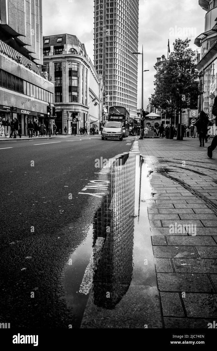 La tour du centre de Londres se reflète sur une flaque sur Tottenham court Road. Banque D'Images