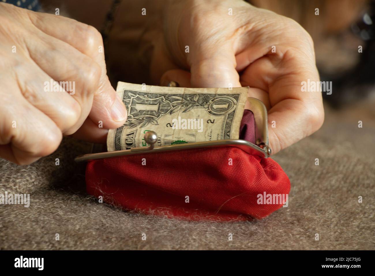 les mains de la vieille femme prennent une facture de dollar d'un portefeuille rouge doux, l'argent dans un portefeuille, la finance Banque D'Images