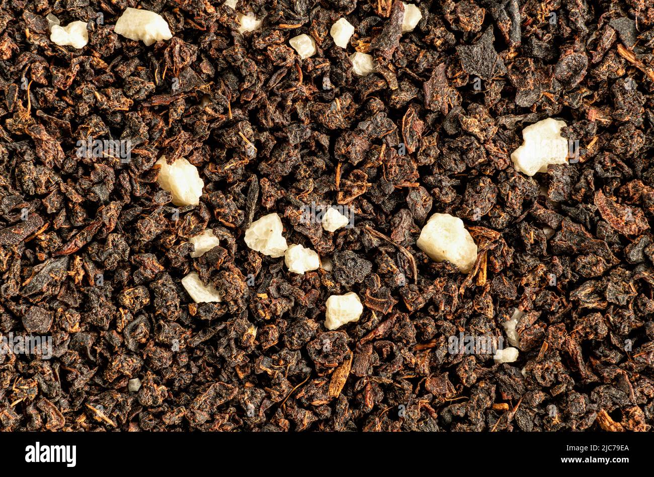 Flocons bruns de thé noir à feuilles volantes provenant de sacs - variété Earl Gray. Les cristaux blancs sont aromatisants artificiels 1,5x grossissement, largeur d'image 23mm Banque D'Images