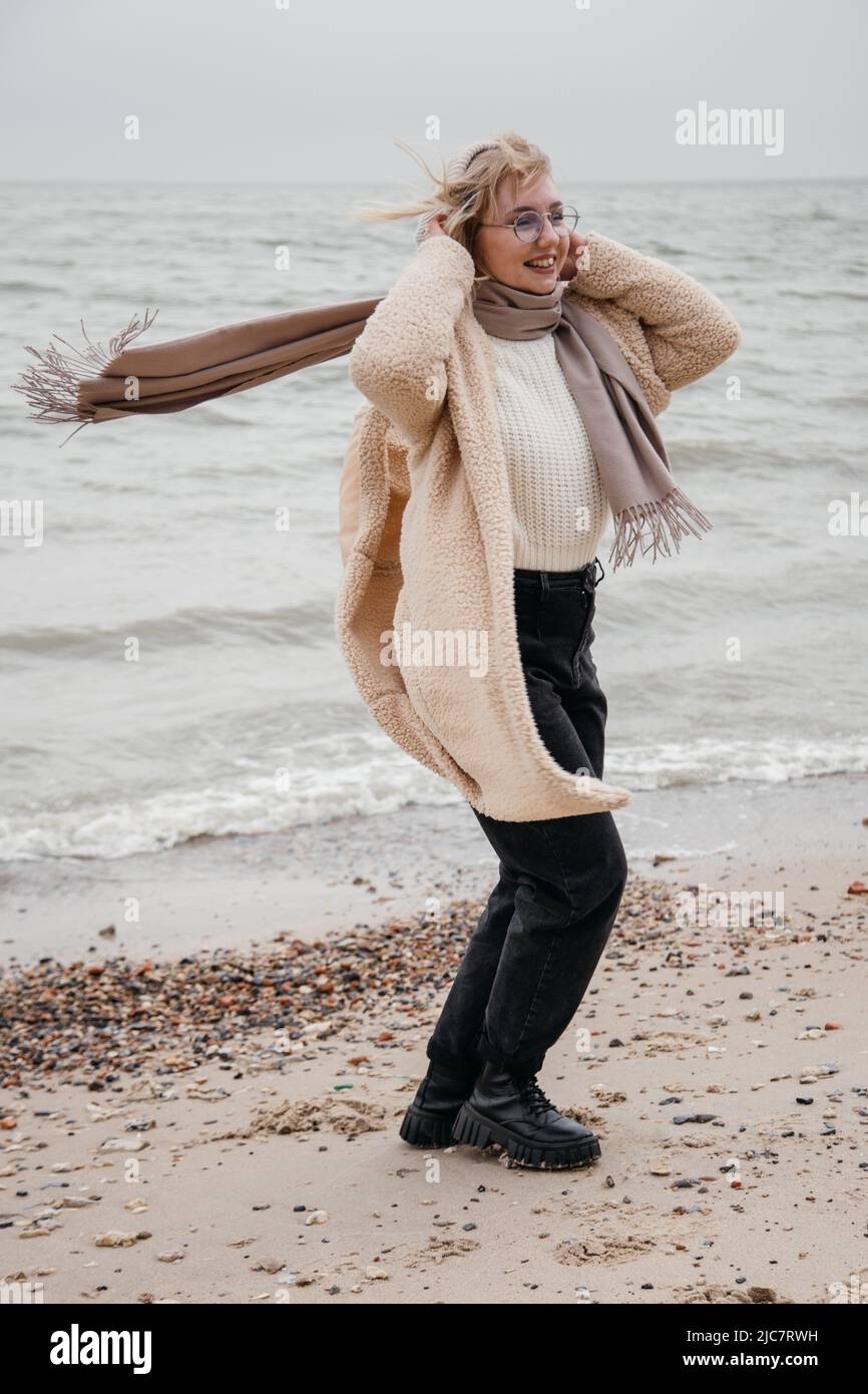 Portrait de jeune femme souriante visage partiellement couvert de cheveux volants par jour venteux. Jolie blonde décontractée sur le fond de la mer. À l'extérieur. Banque D'Images