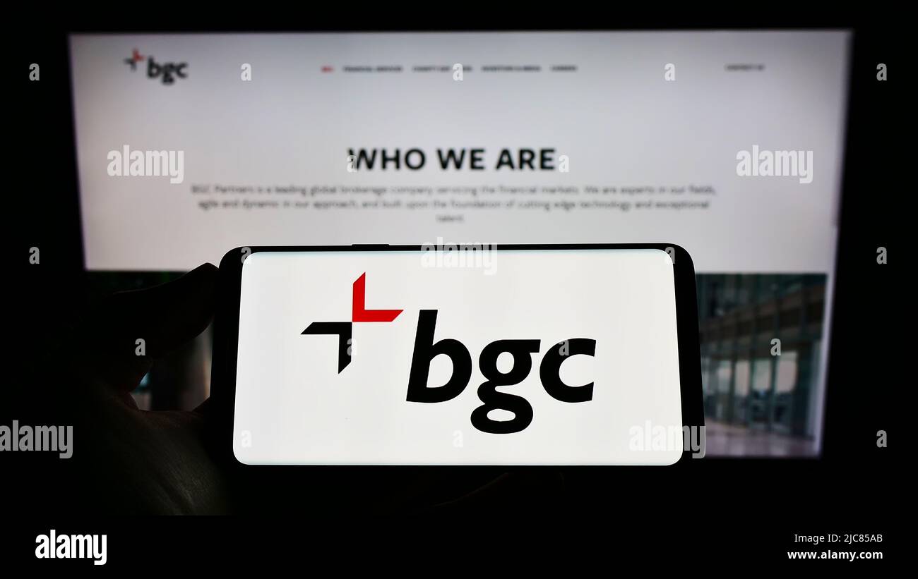 Personne tenant un téléphone cellulaire avec le logo de la société américaine de services financiers BGC Partners Inc. À l'écran devant le site Web. Mise au point sur l'affichage du téléphone. Banque D'Images