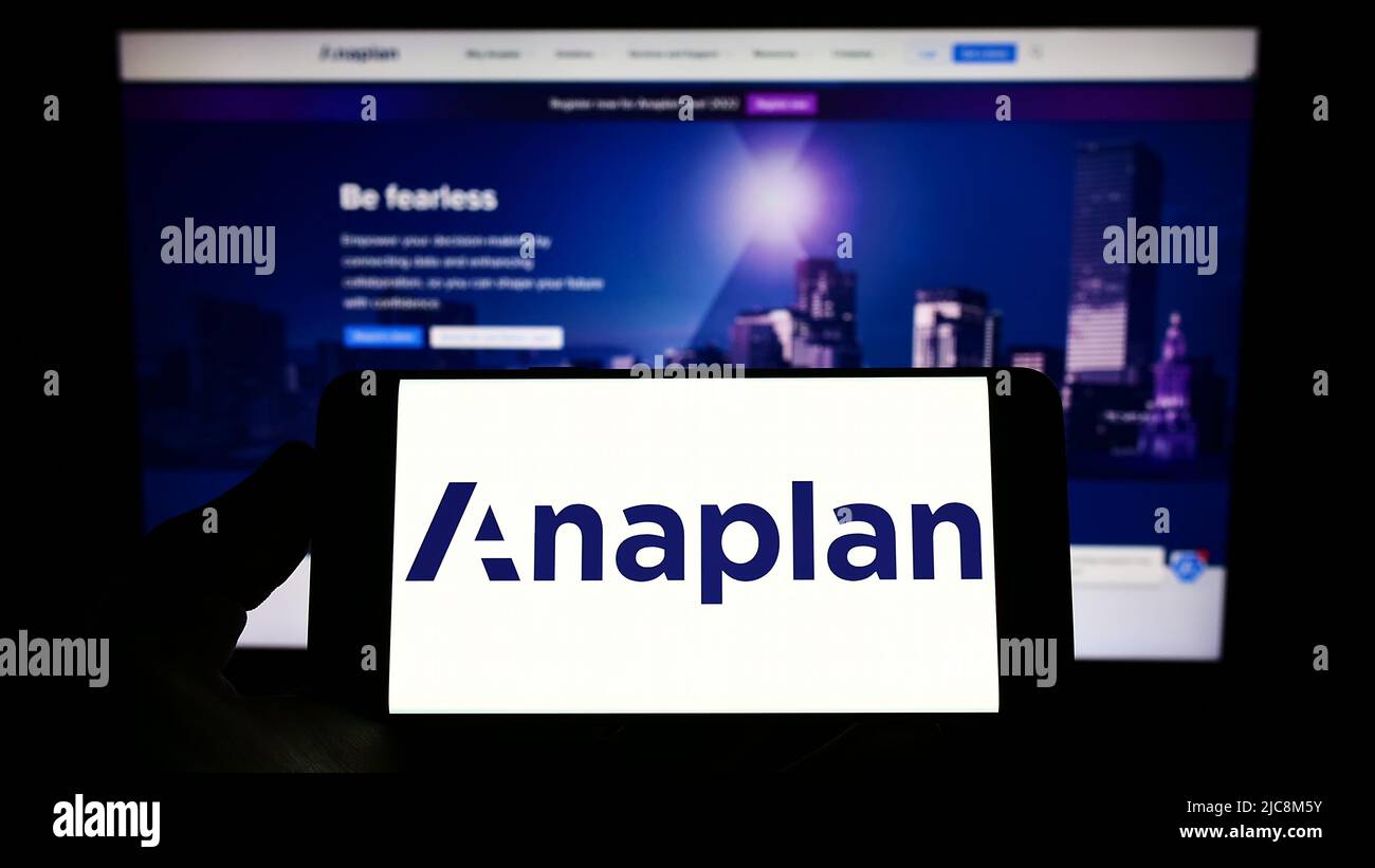 Personne tenant un téléphone cellulaire avec le logo de la société américaine de logiciels Anaplan Inc. À l'écran devant le logo d'affaires. Mise au point sur l'affichage du téléphone. Banque D'Images