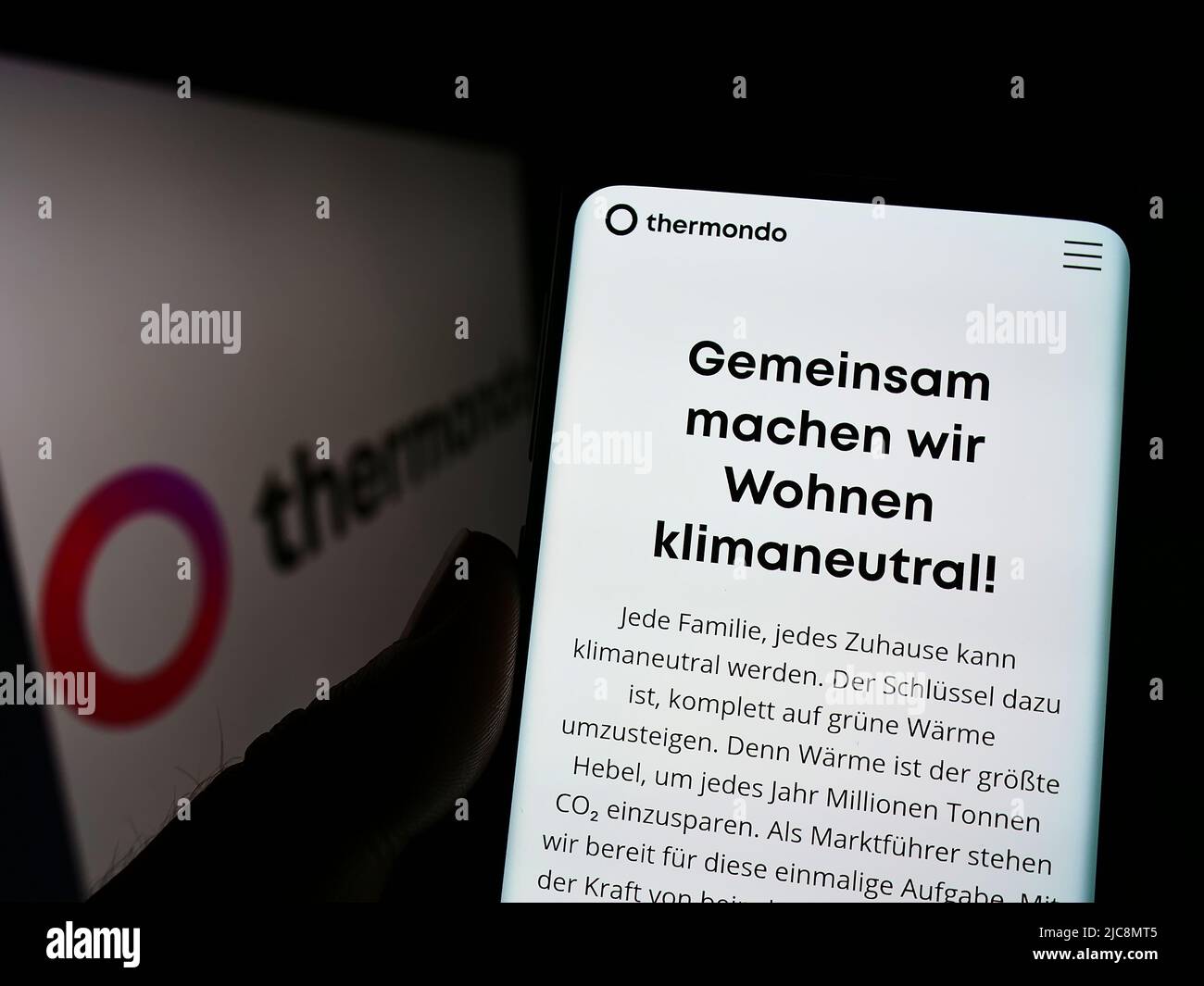 Personne tenant le téléphone portable avec la page web de la société allemande thermondo GmbH de solutions de chaleur à l'écran avec logo. Concentrez-vous sur le centre de l'écran du téléphone. Banque D'Images
