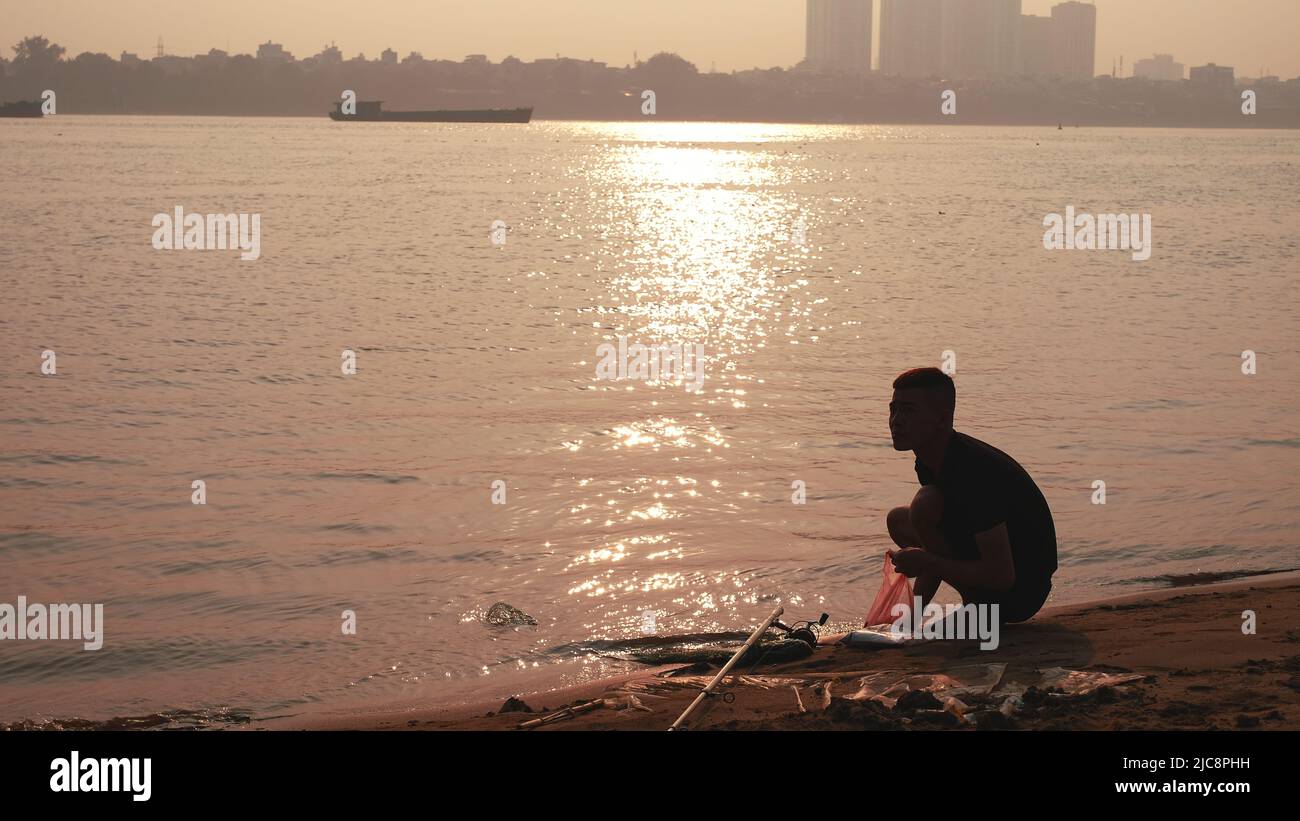 Homme en route à Riverbank Sunset Vietnam Banque D'Images