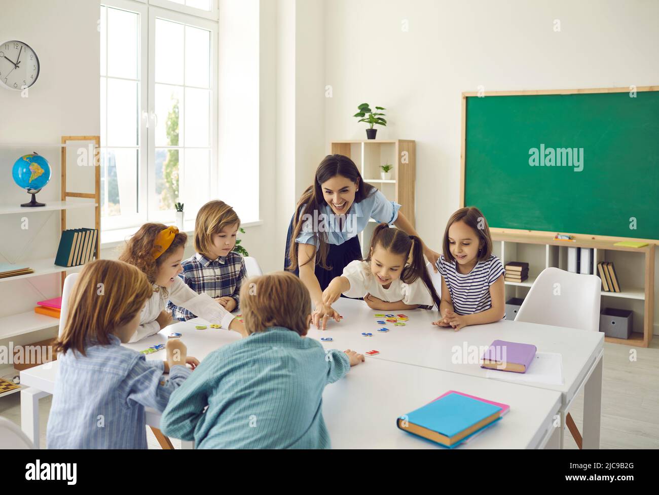 Les enseignantes et les élèves du secondaire junior ont du plaisir à mettre ensemble des puzzles en classe. Banque D'Images