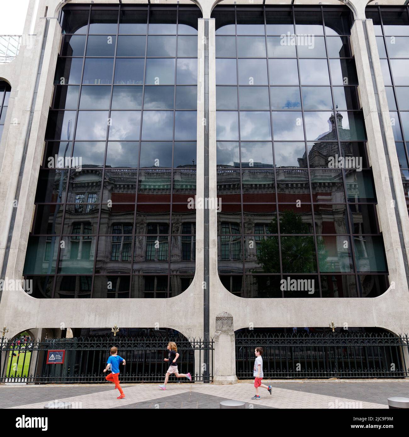 Londres, Grand Londres, Angleterre, 28 mai 2022 : les enfants courent à l'extérieur du Musée national d'histoire tandis que le Musée V&A se reflète dans le verre. Banque D'Images