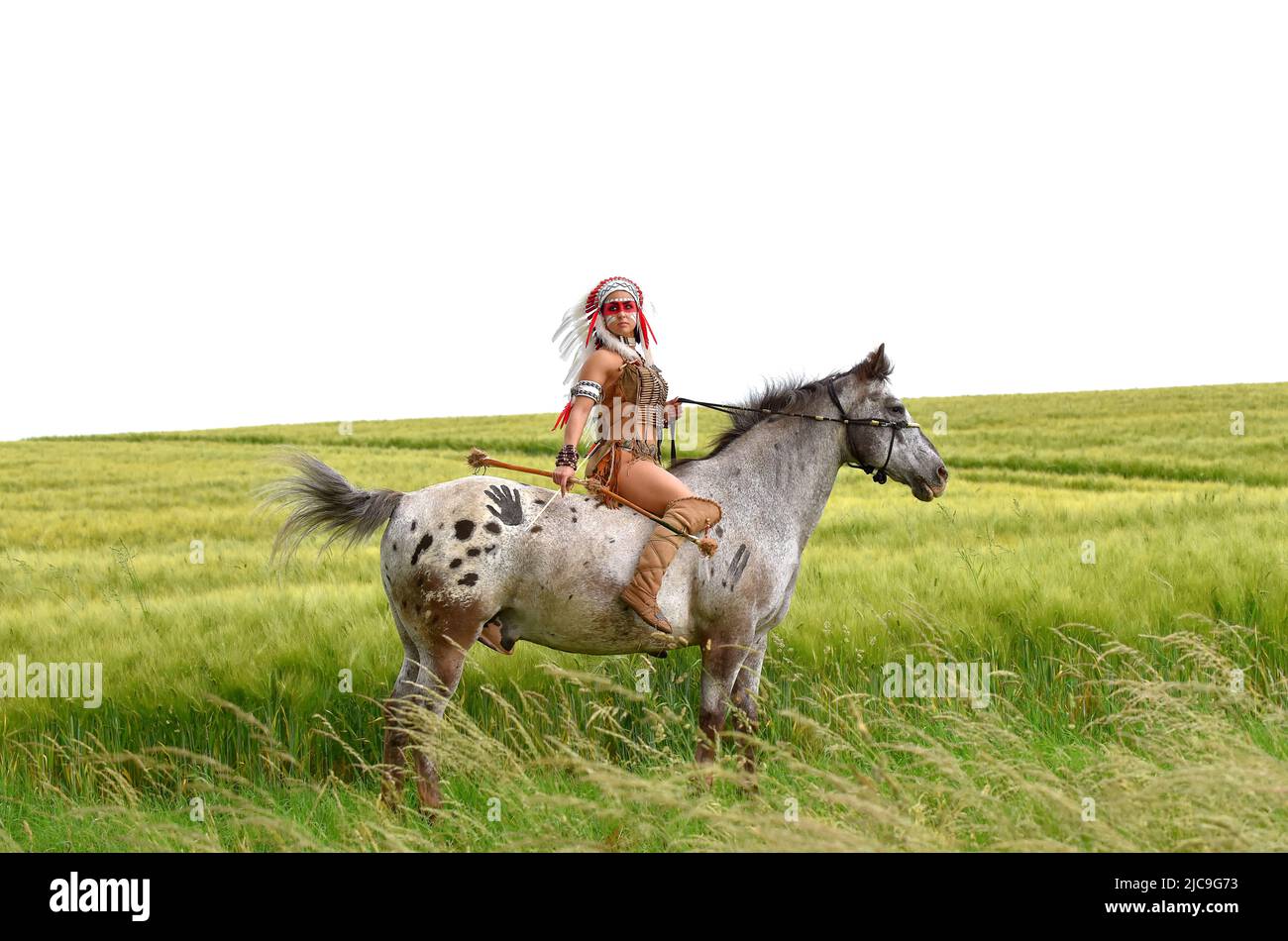 Une femme indienne amérindienne est vue dans la prarie avec son poney. Elle est habillée de vêtements indiens traditionnels et porte une guerre à plumes bonne Banque D'Images