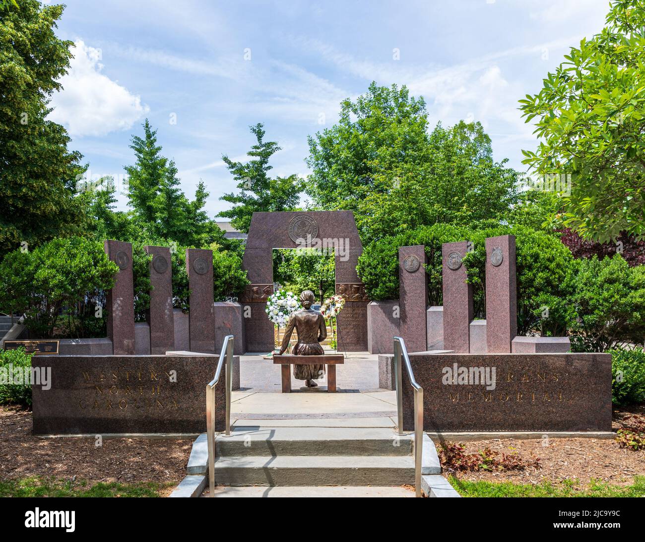 ASHEVILLE, NC, USA-5 JUIN 2022 : le Mémorial des vétérans de la Caroline du Nord de l'Ouest à Pack Square comprend la statue de la femme sur la lettre de lecture du banc. Wrea fleuri Banque D'Images