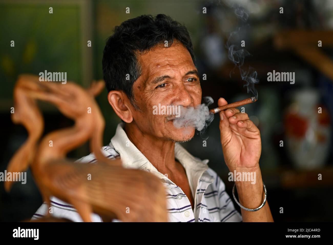 Jakarta, Indonésie. Joyeux homme content fumant un cigare de cheroot dans un magasin de commerce de rue. PHOTO DE SAM BAGNALL Banque D'Images