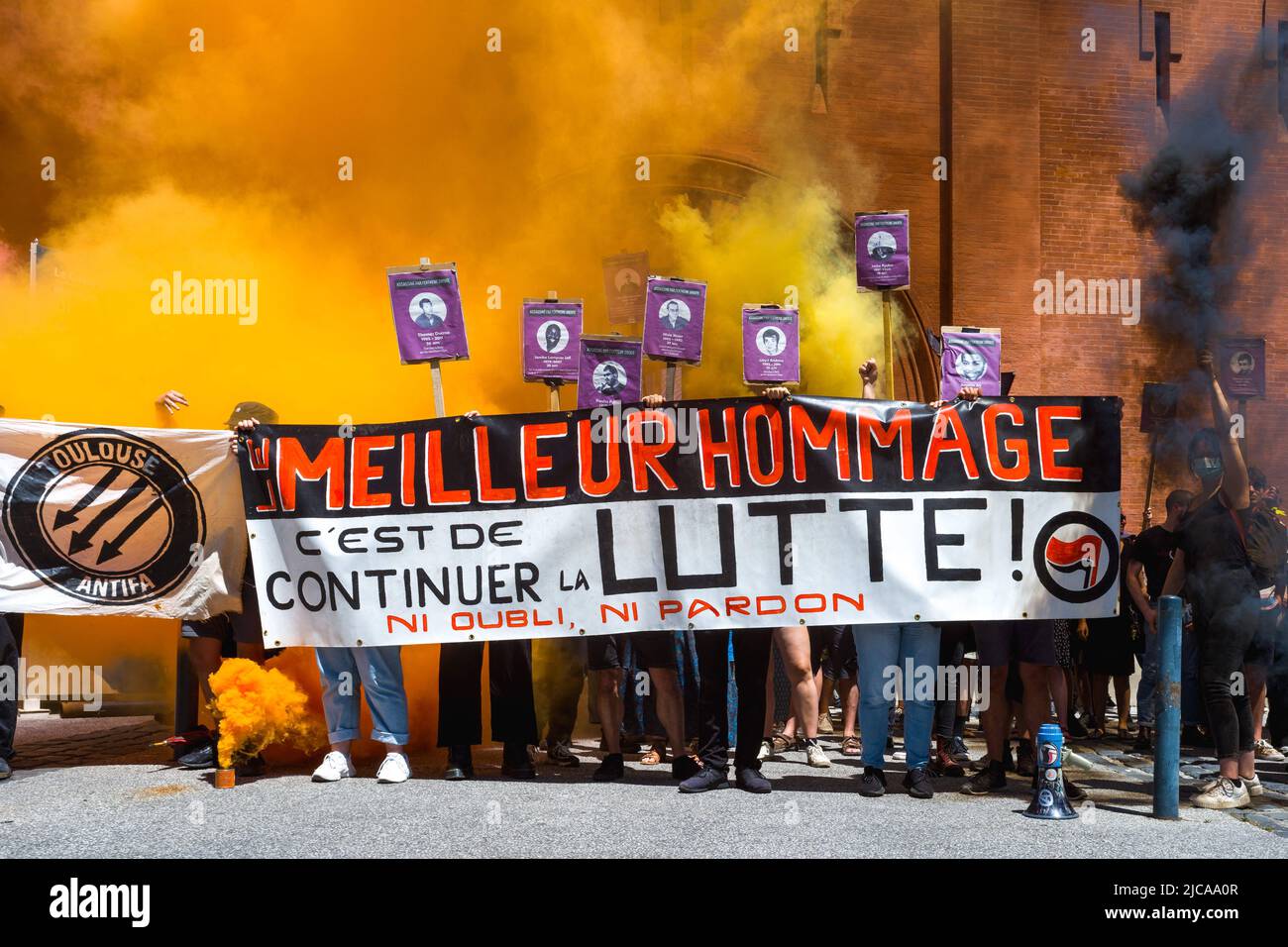 Photo de groupe avec les organisateurs de l'hommage, UAT Union Antifasciste Touloudaine, derrière une bannière, le meilleur hommage est de continuer à se battre! Ni l'oubli, ni le pardon et derrière des affiches avec portraits de victimes et de fumée jaune, rouge et noire, devant l'ancienne prison Saint-Michel de Toulouse. Hommage à Clément Méric devant l'ancienne Maison d'arrêt St Michel à Toulouse, activiste antifasciste, est mort sous les coups d'une tête de peau extrême droite sur 05 juin 2021 à Paris. France, Toulouse le 11 juin 2022. Photo de Patricia Huchot-Boissier/ABACAPRESS.COM Banque D'Images