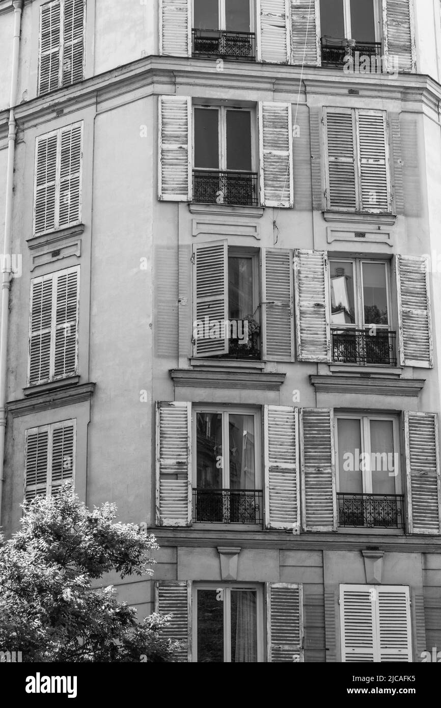 Volets sales sur les fenêtres urbaines aléatoires. Immeuble urbain à logements multiples dans un état de déréparation. Banque D'Images