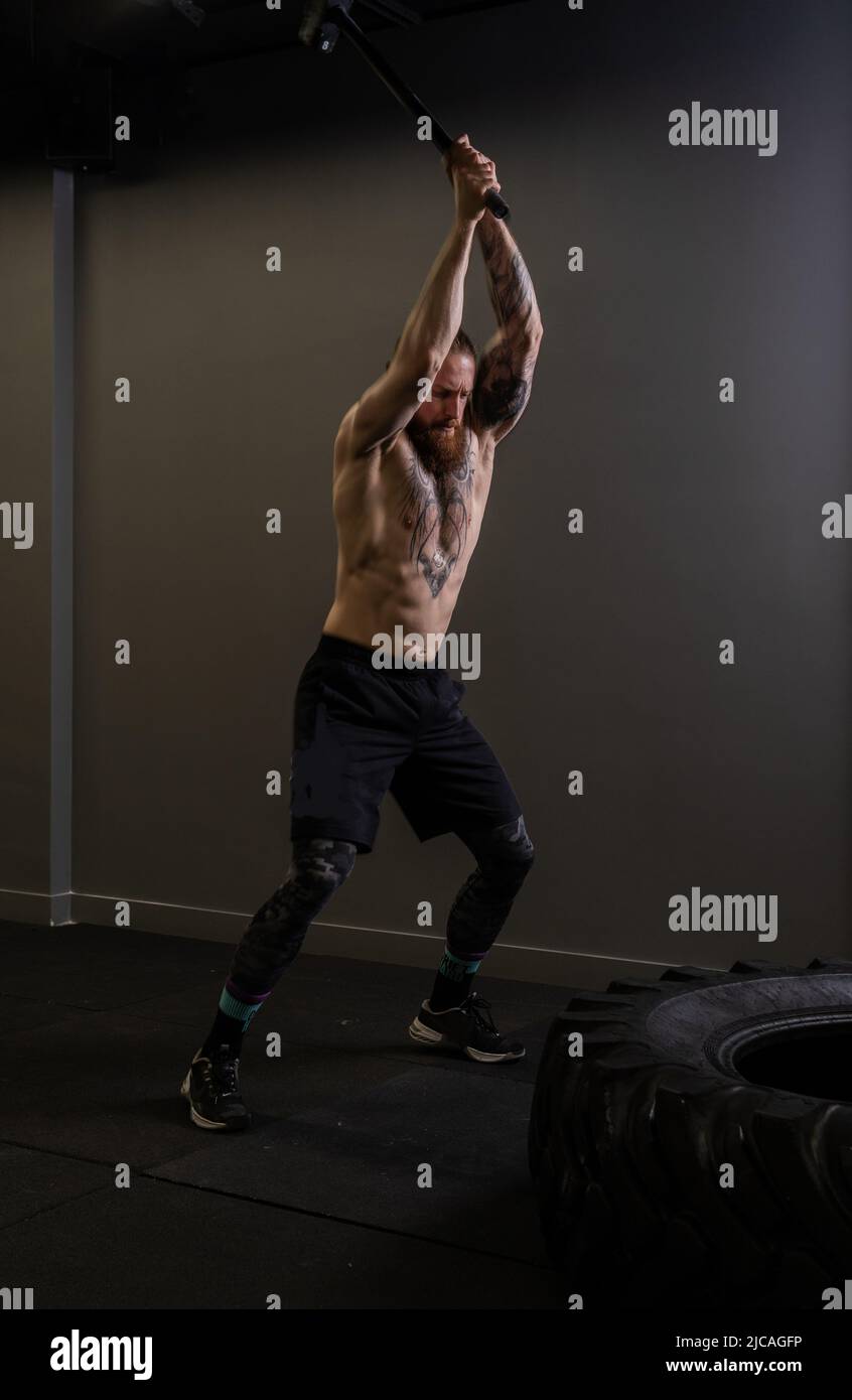 Pneu marteau de traîneau musclé roue homme frapper exercice force d'entraînement, concept équipement fort d'athlétisme de concentration de sportswear, homme Banque D'Images