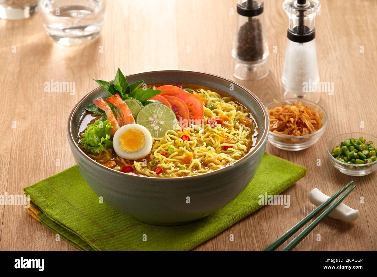 un bol de nouilles cuites aux crevettes, aux œufs durs, aux tomates, aux légumes et aux tranches de ​​chili et aux oignons frits Banque D'Images