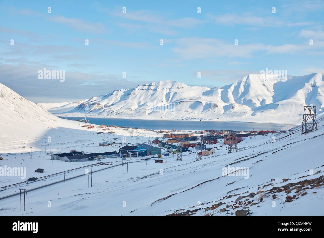Vue d'ensemble des maisons colorées de Longyearbyen, placées au bord de la mer entre les hautes montagnes enneigées, donnent un ciel bleu clair Banque D'Images