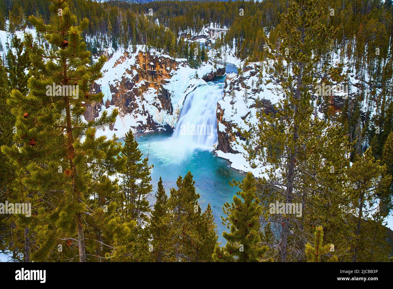 Des pins encadrent des cascades bleues sereines en hiver à Yellowstone Banque D'Images