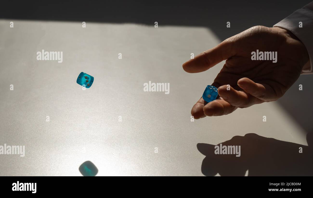 Femme lance une paire de dés bleus transparents. Banque D'Images