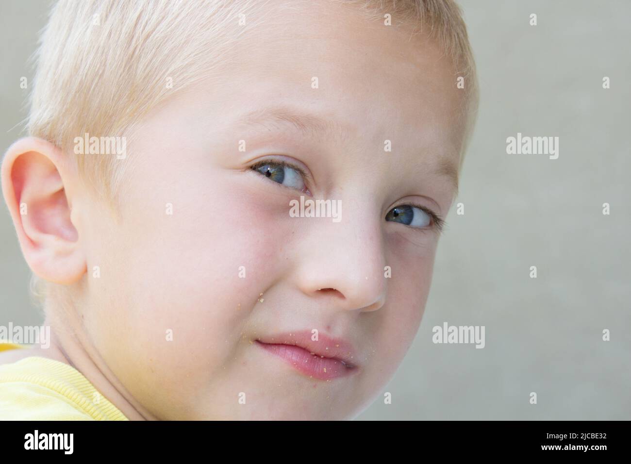 beau garçon blond avec les yeux bleus regardé sur les côtés portrait Banque D'Images