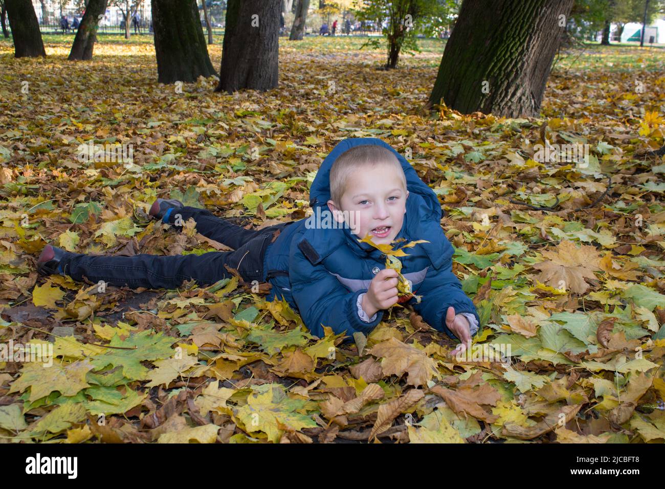 garçon allongé sur des feuilles d'érable dans le parc Banque D'Images