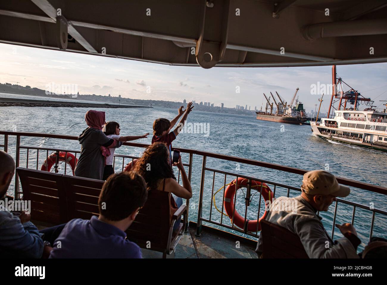 Istanbul, Turquie. 11th juin 2022. Les enfants se font la vague devant les personnes voyageant dans les lignes de ferry de la ville au Bosphore d'Istanbul. Crédit : SOPA Images Limited/Alamy Live News Banque D'Images