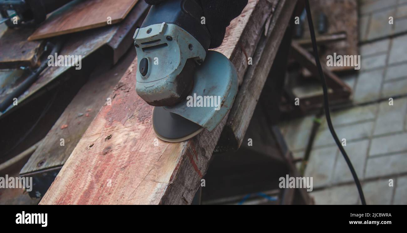 un homme meule une planche. Élimination de l'ancienne peinture des panneaux. Travail de menuiserie. Concentration sélective Banque D'Images