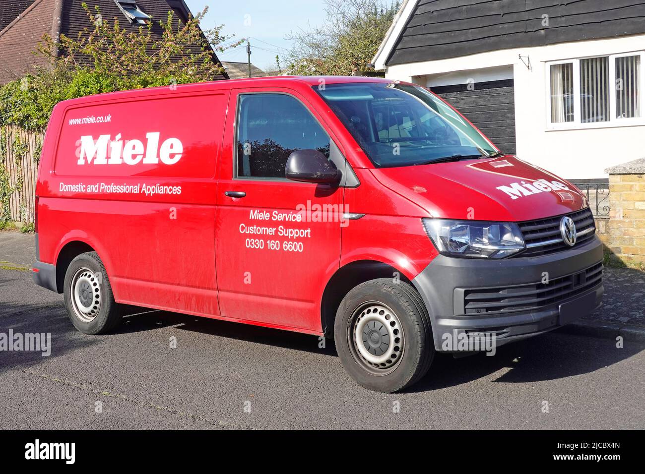 Les ingénieurs ont Red Volkswagen VW Miele van pour les appareils domestiques et professionnels en mettant le service clientèle en stationnement sur la route résidentielle Essex Angleterre Royaume-Uni Banque D'Images