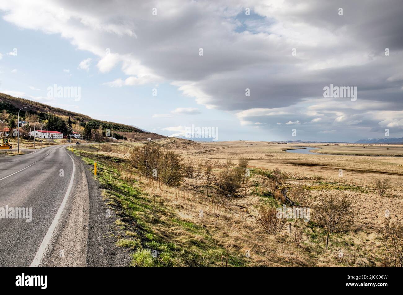 Paysage avec une route asphaltée à travers une large vallée sous un ciel avec des nuages spectaculaires près de Varmahlíð en Islande Banque D'Images