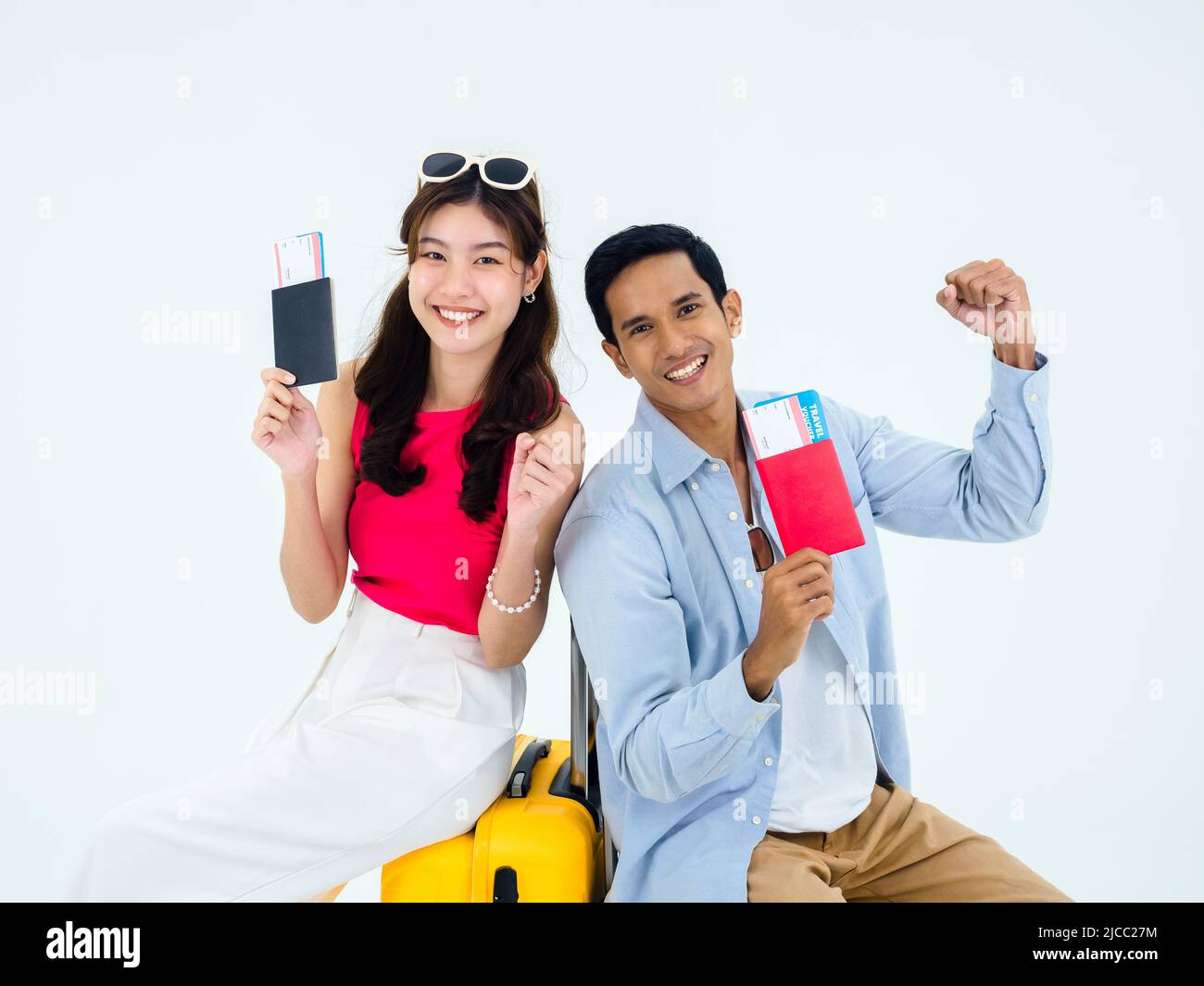 Prêt à voyager, joyeuses vacances. Concept de vacances d'été. Un couple asiatique souriant tenant le poing levé, montrant passeport avec succès, jeune femme et homme Banque D'Images