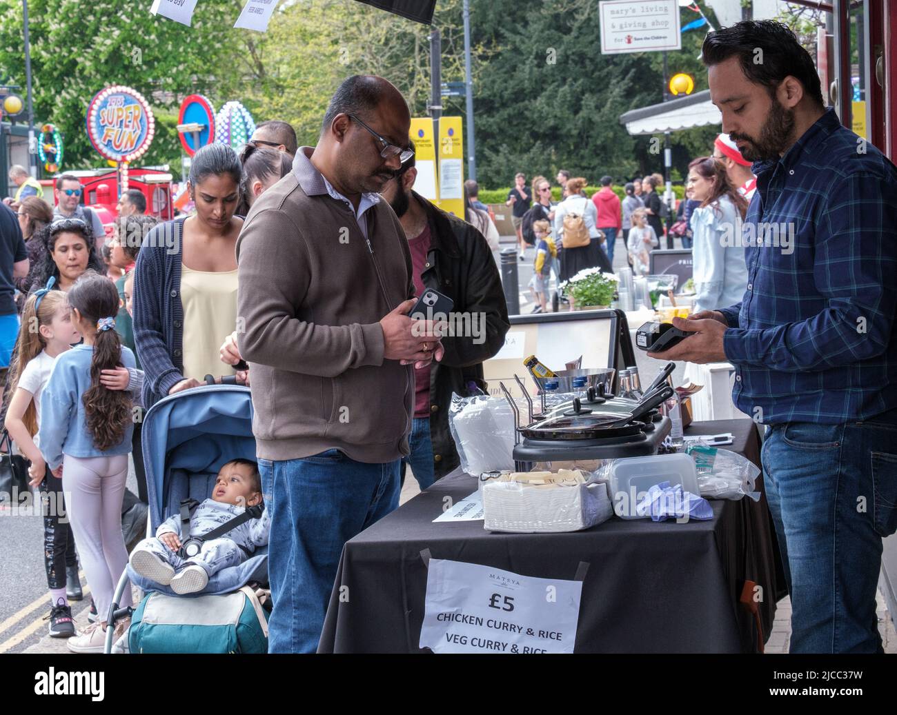 Un homme achète du curry de poulet et du riz dans une cabine à l'extérieur du restaurant de cuisine indienne Matsya au St George's Day Celebration 2022, Pinner, Harrow, Londres. Banque D'Images