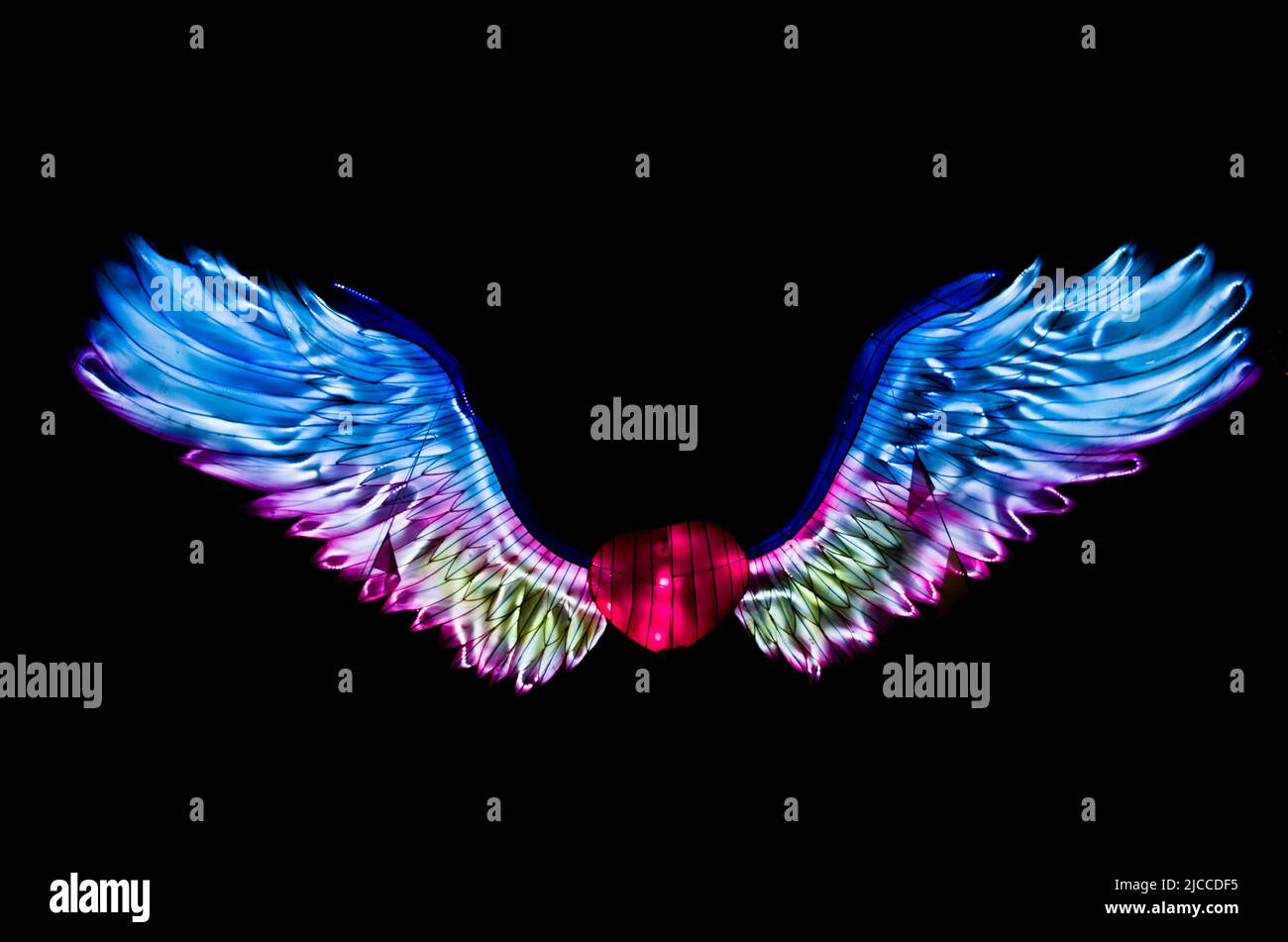 Une magnifique sculpture légère d'un coeur avec des ailes ressemblant à une couverture d'album rock de 80s contre une nuit noire au Lightopia Festival à Londres Banque D'Images