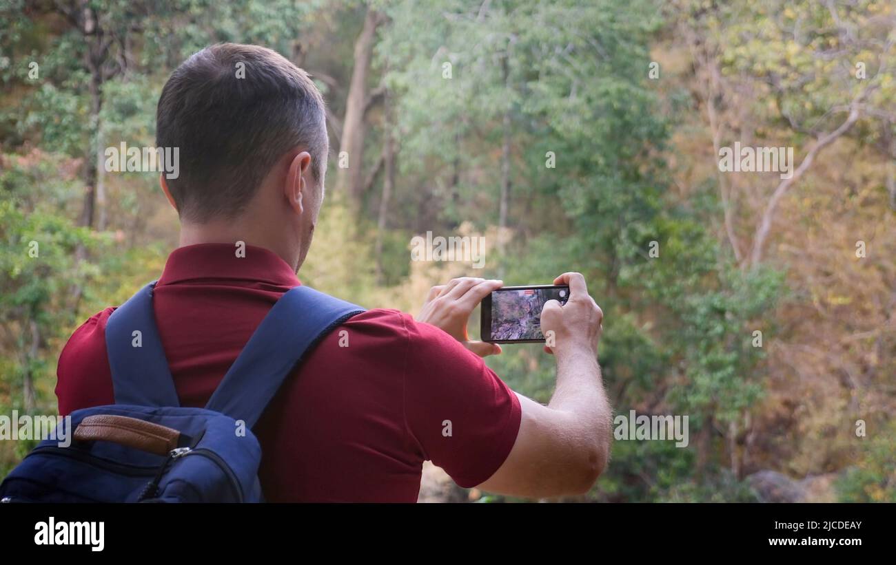 Un blogueur de voyageurs avec sac à dos dans la nature filmant de la vidéo sur l'appareil photo de smartphone Banque D'Images