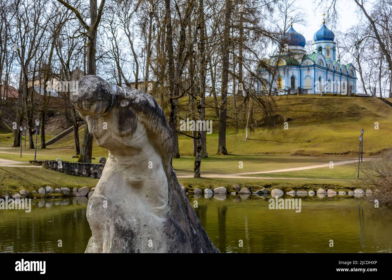 Sculpture en travertin - une figure d'un homme avec un lourd fardeau au bord de la marche menant à l'étang dans la colline du parc du château de Cesis, Lettonie Banque D'Images