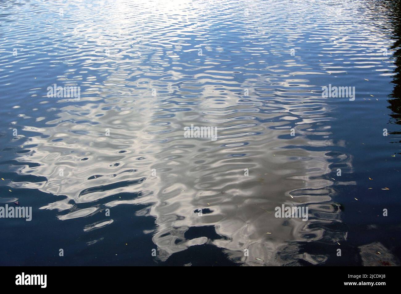 Ciel bleu et nuages moelleux déformés sur l'eau Banque D'Images