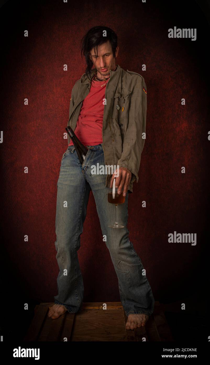 Junkie homme avec cheveux noirs et bouteille avec joint près du mur rouge vintage Banque D'Images