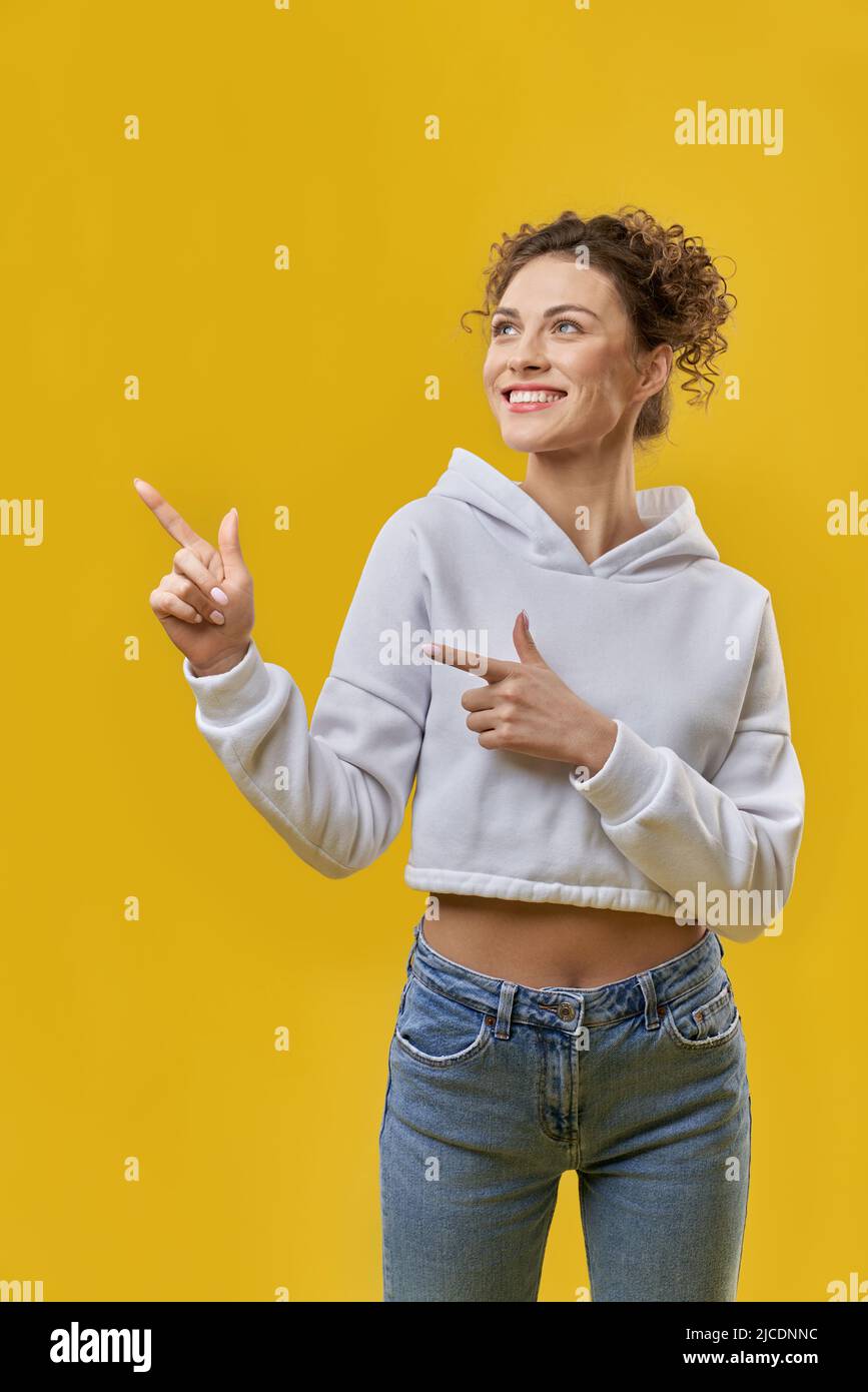 Jolie fille caucasienne indiquant avec des index dans la bonne direction, regardant loin à l'intérieur. Portrait d'une fille souriante pointant vers l'extérieur, isolé sur fond orange studio, espace de copie. Concept de gestuelle. Banque D'Images Jolie fille caucasienne indiquant avec des index dans la bonne direction, regardant loin à l'intérieur. Portrait d'une fille souriante pointant vers l'extérieur, isolé sur fond orange studio, espace de copie. Concept de gestuelle. Banque D'Images