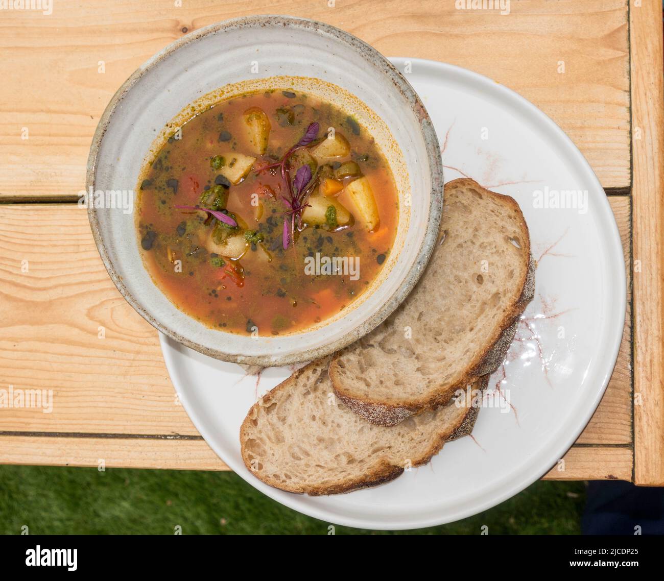 Un bol de soupe aux tomates et aux épinards servi avec du pain au levain Banque D'Images