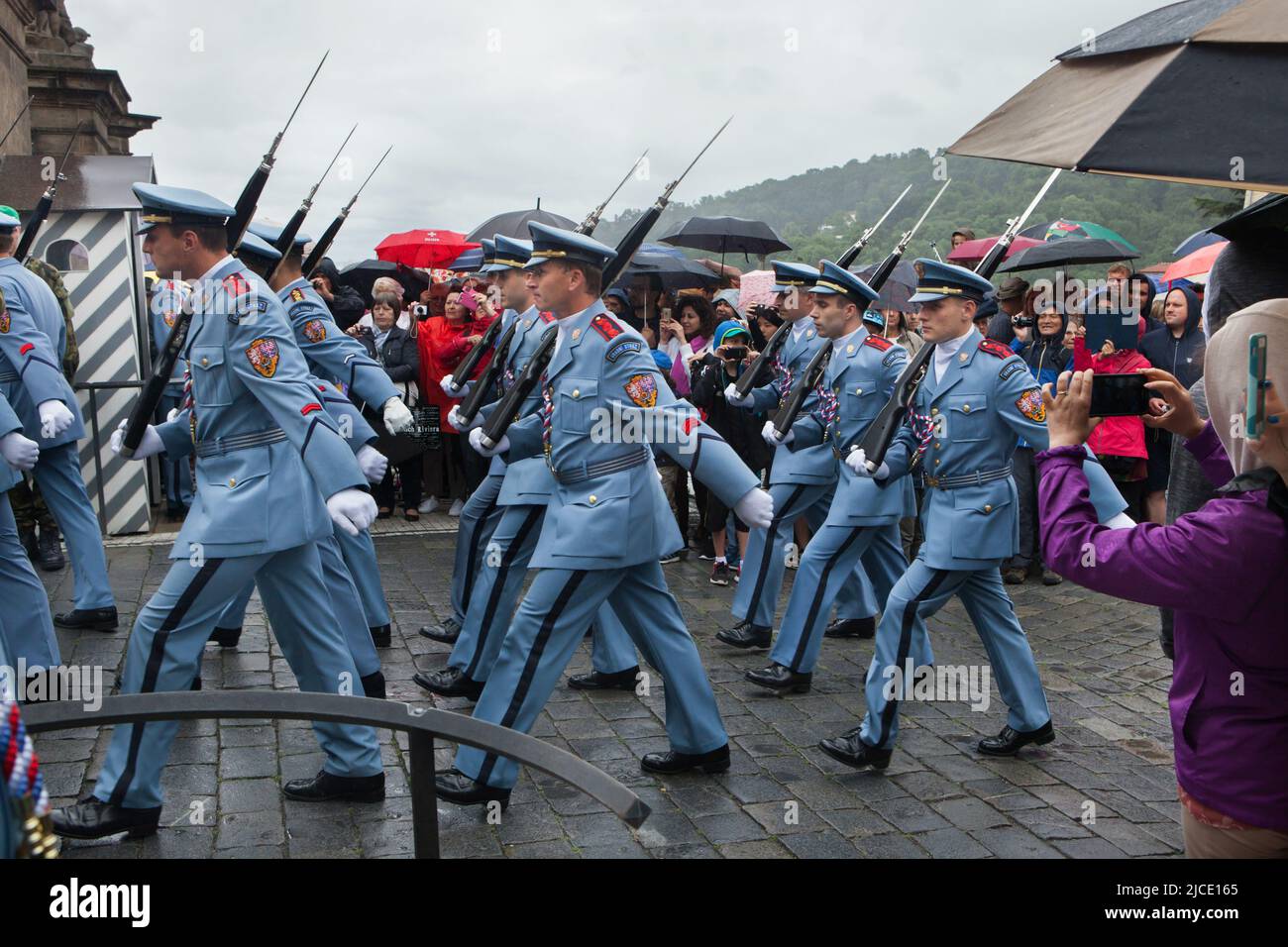 Les touristes regardent sous la pluie la cérémonie de la relève de la garde du château (Hradní stráž) devant le château de Prague sur la place Hradčanské à Prague, en République tchèque. Banque D'Images