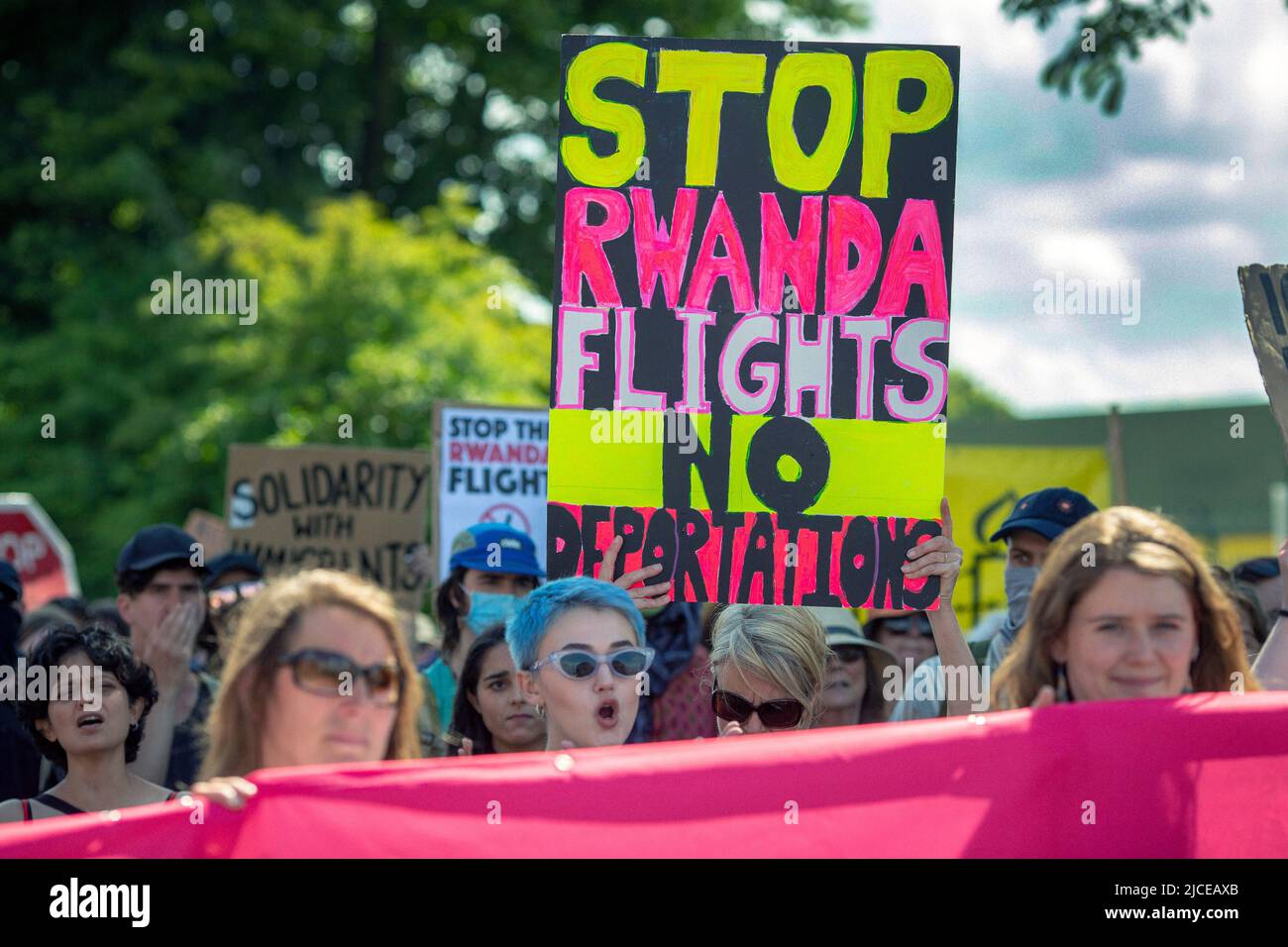 Les manifestants branchent et tiennent des pancartes contre les vols d'expulsion du Royaume-Uni vers le Rwanda, près du Brook House Immigration Removal Centre sur 12 juin 2022 à Londres Banque D'Images