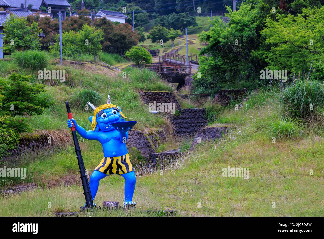 Statue de démon bleu avec grand club et bol dans la campagne du Japon Banque D'Images