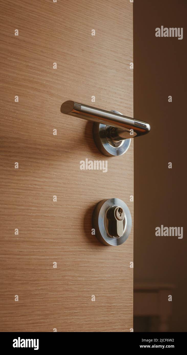 Poignée de porte métallique moderne sur porte de chambre en carton de densité moyenne, mise au point sélective Banque D'Images