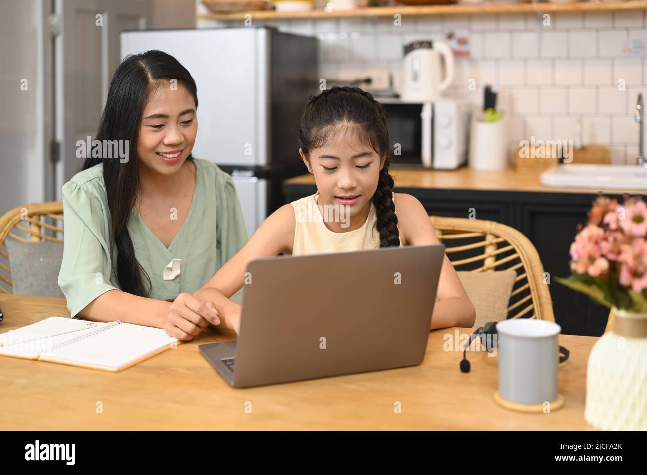 Mère asiatique aidant sa petite fille à faire ses devoirs, étudiant par le biais du système d'apprentissage en ligne Banque D'Images