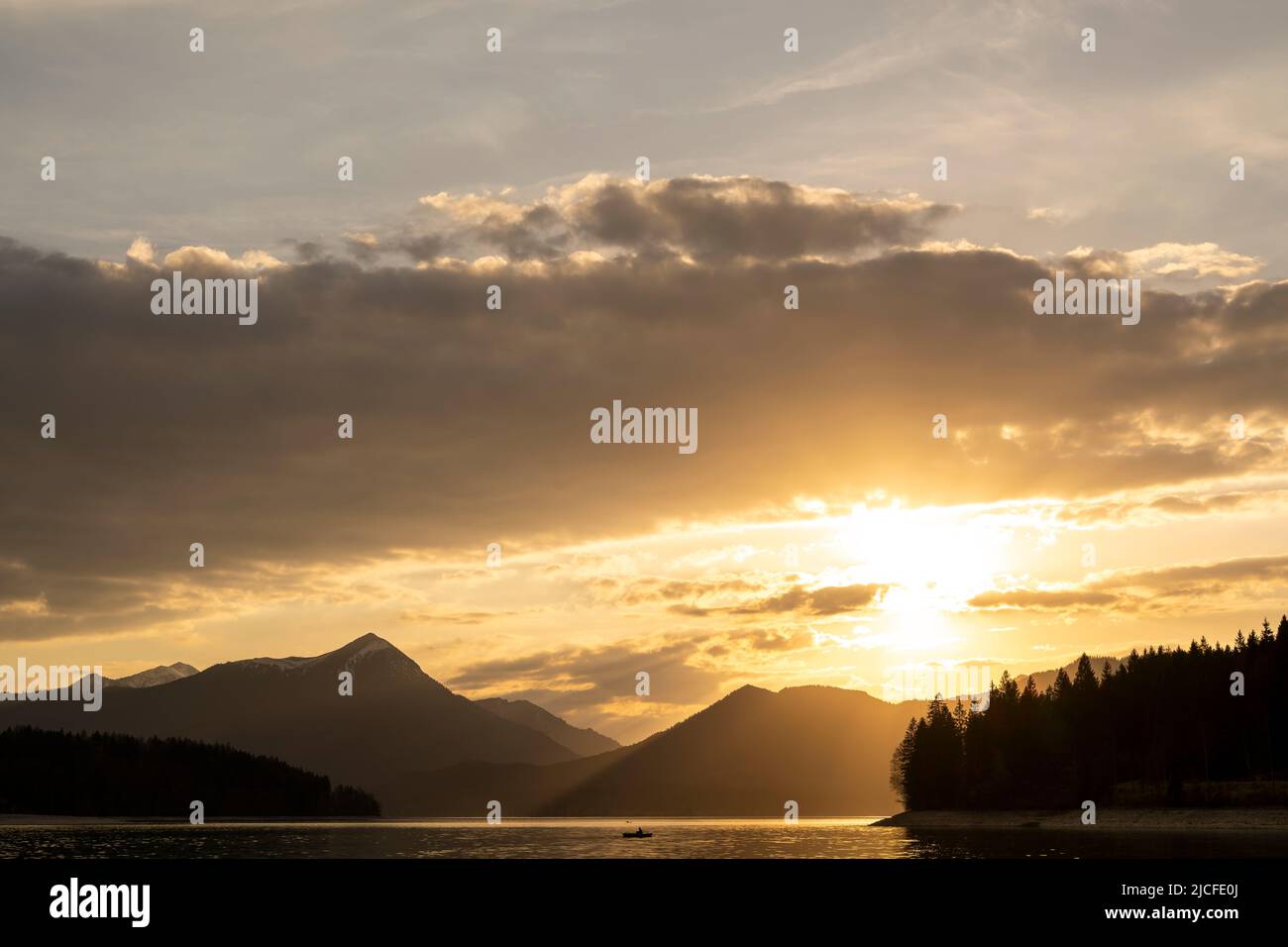 Ambiance nocturne peu avant le coucher du soleil à Walchensee dans les Alpes bavaroises, en premier plan un pêcheur à la ligne dans un bateau à ramer, en arrière-plan le Simetsberg, atmosphère nuageux et le soleil couchant. Banque D'Images Ambiance nocturne peu avant le coucher du soleil à Walchensee dans les Alpes bavaroises, en premier plan un pêcheur à la ligne dans un bateau à ramer, en arrière-plan le Simetsberg, atmosphère nuageux et le soleil couchant. Banque D'Images