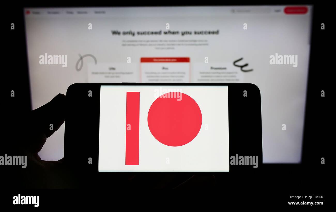 Personne détenant un smartphone avec le logo de la société américaine de plate-forme d'adhésion Patreon Inc. À l'écran devant le site Web. Mise au point sur l'affichage du téléphone. Banque D'Images