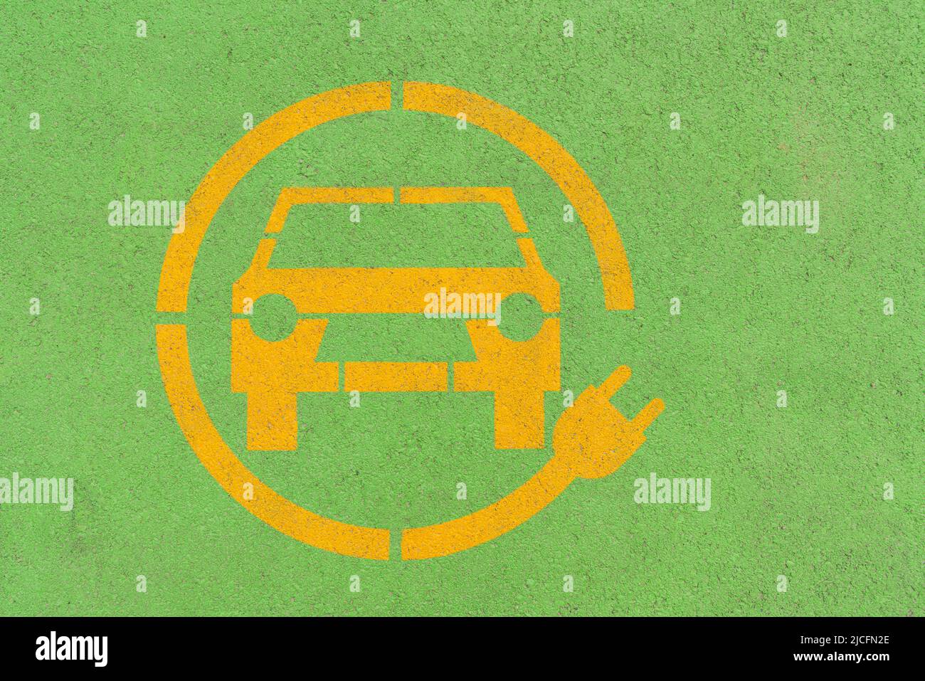 Symbole de voiture électrique jaune sur asphalte vert. Parking de chargement de véhicule électrique Banque D'Images